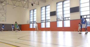 Okulda basketbol oynamak, öğrenciler koç ve takım arkadaşlarıyla antrenman yapmak. Spor, atletizm, takım çalışması, antrenman, egzersiz, koçluk.