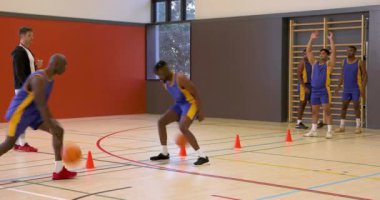 Basketbolcular spor salonunda salya akıtma tekniklerini antrenman yaparken koç cesaretlendiriyor. Spor, antrenman, antrenman, takım çalışması, egzersiz, yetenek geliştirme
