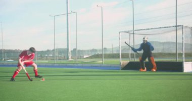 Çim hokeyi oynuyor, oyuncu kaleciyle şut atmaya hazırlanıyor. Spor, saha sporları, takım sporları, yarışma, atlet, aksiyon