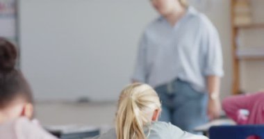 Okulda, kız kalemle elini kaldırıyor, bayan öğretmene dikkat ediyor. Eğitim, öğrenim, sınıf, öğrenim, katılım, katılım