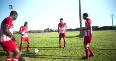 Sahada futbol oynuyor, kırmızı üniformalı bir grup adam pas veriyor. Takım çalışması, spor, yarışma, atletik, açık hava, etkinlik