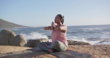 Okyanus kenarında farkındalık, yoga minderi üzerinde meditasyon yapan Asyalı kadın, fotokopi alanı. Meditasyon, rahatlama, sağIık, dinginlik, sükunet, zindelik