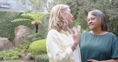 Gülümseyen çok ırklı son sınıf bayan arkadaşları bahçede muhabbet edip kaynaşıyorlar. dostluk, bağlantı, açık hava, mutluluk, yaşam tarzı, yaşlılar