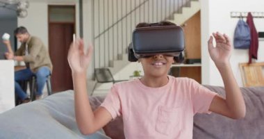 VR kulaklık takan, Hintli baba dizüstü bilgisayarla çalışırken el sallayan ve gülümseyen bir çocuk. Sanal gerçeklik, teknoloji, aile, bağlanma, dijital, etkileşim