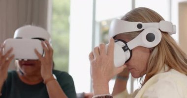 VR kulaklıkları kullanarak, çok ırklı son sınıf bayan arkadaşları evde sanal gerçeklik deneyiminin tadını çıkarıyorlar. Teknoloji, yenilik, eğlence, kadın, arkadaşlık, eğlence