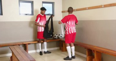 Futbol antrenmanı, soyunma odasında takım üniforması giyen iki oyuncu. Takım çalışması, sporcular, spor, hazırlık, dostluk