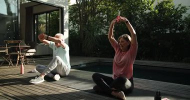 Son sınıf çifti güneşli verandada birlikte yoga seansının keyfini çıkarıyorlar. Sağlık, egzersiz, rahatlama, spor