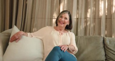 Evdeki kanepede oturan gülümseyen yaşlı kadın, sıcak tatil atmosferinin tadını çıkarıyor. Yaşlılar, rahatlama, sıcaklık, dinginlik, yaşam tarzı