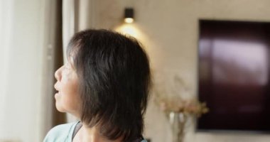 Evde madalyalarıyla kıdemli Asyalı kadın, içten gülümsüyor ve kutluyor. Yaşlılar, kutlama, şenlik, mutluluk, neşe