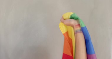 Elinde gökkuşağı bayrağı, kolunda gurur renkleri olan biri. LGBT, topluluk, eşitlik, kutlama, çeşitlilik, kapsama