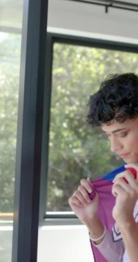 Dikey video: Kimliği gururla kucaklayan, evinde canlı gökkuşağı bayrağına sarılmış kişi. LGBT, gurur, çeşitlilik, kapsayıcılık, temsil, kendini ifade etme