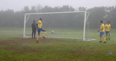 Futbol oynamak, koçun rehberliğinde sisli sahada antrenman yapmak. Spor, takım çalışması, antrenman, antrenman, egzersiz, açık hava