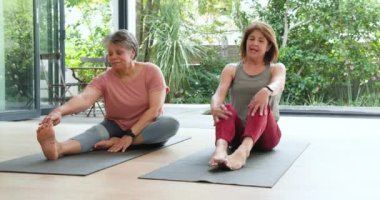 Evde yoga minderleri üzerinde esneyen, sohbet ve egzersizden zevk alan son sınıf kadınları. Zindelik, fitness, arkadaş, egzersiz, sağlık, rahatlama.