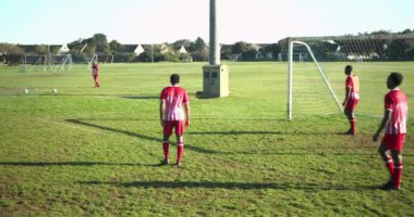 Futbol oynuyor, kırmızı üniformalı iki adam kale direğinin yanındaki sahada antrenman yapıyor. Spor, takım çalışması, antrenman, egzersiz, spor