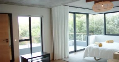 Geniş pencereli, beyaz perdeli modern yatak odası ve düzgün düzenlenmiş yatak örtüleri, fotokopi alanı. İç mekan, minimalist, dekor, ışık