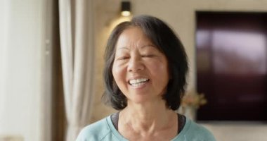 Gülümseyen kıdemli Asyalı kadın evde dinleniyor, huzurlu anın tadını çıkarıyor. Yaşlılık, rahatlama, dinginlik, sükunet, rahatlık, yaşam tarzı