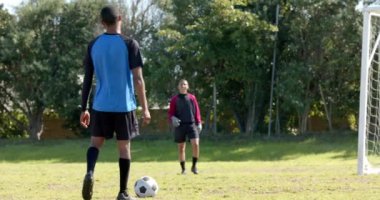 Kaleci güneşli bir günde açık hava maçında futbol topunu kurtarmak için dalıyor. aksiyon, spor, yarışma