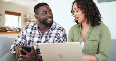 Evde akıllı telefon ve dizüstü bilgisayar kullanan mutlu çok ırklı çift birlikte vakit geçiriyorlar. Aile, teknoloji, yaşam tarzı, dijital, bağlantı, mutluluk