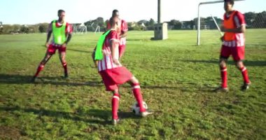 Sahada futbol oynayan, kırmızı üniformalı erkek oyuncular kaleye doğru koşuyor. Spor, rekabet, takım çalışması, aksiyon, sporcular