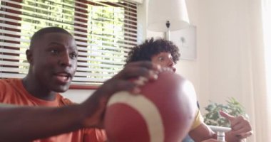 Coşkuyla tezahürat yapan iki çok ırklı erkek arkadaş evde futbol maçı izliyorlar. Spor, coşku, dostluk, hayranlar, heyecan, televizyon