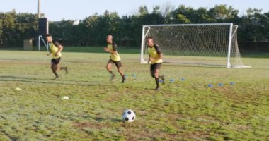 Futbol oynayan, antrenman sırasında yakın sahada koşan erkekler. Spor, futbol, antrenman, takım çalışması, sporcular, egzersiz