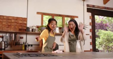 Çok ırklı büyükanne ve genç kadın mutfakta yemek hazırlıyor, evde neşeli anlar paylaşıyorlar. Yemek, birliktelik, kutlama, mutluluk, tatil, yemek hazırlama