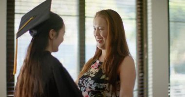 Mezuniyet şapkalı kızına sarılmak, Asyalı bir anne evde başarısını kutluyor. Kutlama, aile, mutluluk, gurur, eğitim, başarı