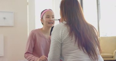 Makyaj yapıyor, Asyalı anne evde kızın yüzüne dikkatlice fırça sürüyor. Güzellik, aile, bağ, kozmetik, ebeveynlik, gündelik