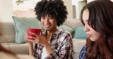 Birlikte gülerek, kadın arkadaşlar Noel kutlaması sırasında evde sıcak içeceklerin tadını çıkarıyorlar. Tatil, şenlikli, kış, toplanma, sıcak, dostluk