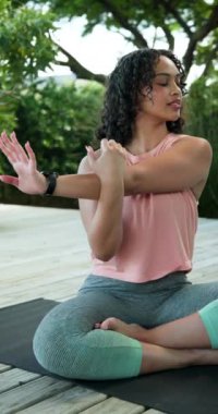 Dikey video: Güvertede yoga yapan kadın, kollarını uzatıyor ve açık havada sükunetin tadını çıkarıyor. Sağlık, meditasyon, fitness, denge, rahatlama, egzersiz