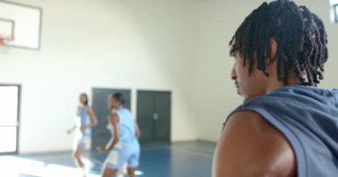 Su içmek, bayan basketbolcu takım arkadaşlarının sahada antrenman yapmasını izlemek, kopyalama alanı. Spor, atlet, hidrasyon, eğitim, takım çalışması, fitness