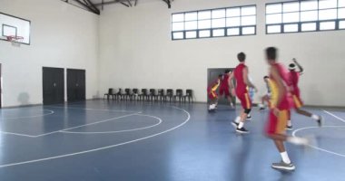Basketbolcular kapalı sahada, basketbolu hedefleyerek yoğun bir şekilde yarışıyorlar. Sporcular, müsabakalar, takım sporları, skor, koçluk, fitness
