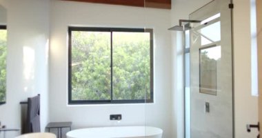 Serbest küveti ve yeşil manzaralı geniş pencereli modern banyo, kopyalama alanı. Lüks, iç mekan, minimalist, çağdaş, temiz, spa