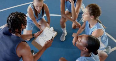 Basketbol koçu sahada bayan takımla maç stratejisini tartışıyor. Koçluk, takım çalışması, spor, kadınlar, tartışma, eğitim