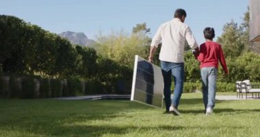 Hintli baba ve oğul arka bahçede yüzme havuzu ve sandalyelerin yanında yürüyorlar. Aile, kaynaşma, açık hava, yaz, rahatlama, boş zaman