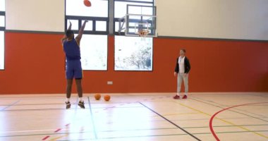 Basketbol antrenmanı, antrenör ve oyuncu spor salonunda top sürme becerilerine odaklanıyor. Spor, koçluk, antrenman, takım çalışması, atlet, egzersiz