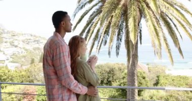 Çeşitli çiftler balkondan okyanus manzarasını seyrediyor, ellerinde kahve tutuyorlar, kendilerini huzurlu hissediyorlar. İlişki, rahatlama, yaşam tarzı