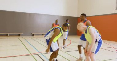 Okuldaki spor salonunda basketbol oyuncuları takım çalışması ve strateji yapıyor. Spor, atletizm, antrenman, yarışma, antrenman