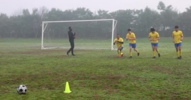 Futbol koçu genç oyuncuları kale direği ve koni ile sahada çalıştırıyor. Spor, antrenörlük, takım çalışması, gençlik, egzersiz, spor