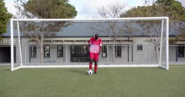 Futbol oynayan, Afrika kökenli Amerikalı erkek sporcu sahada yaya olarak topu dengeliyor. Spor, futbol, rekabet, takım çalışması, aktif, fitness