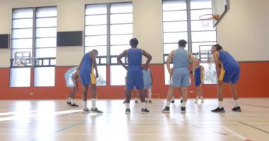 Basketbol oynuyorlar, spor salonundaki öğrenciler maç sırasında basketbol izliyorlar. Spor, rekabet, takım çalışması, etkinlik, fitness