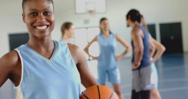 Üniformalı, gülümseyen bayan basketbolcu takım arkadaşlarıyla spor salonunda duruyor, fotokopi odası. Spor, atlet, yarışma, spor salonu, yoldaşlık, fitness