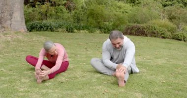 Olgun bir çift dışarıda esniyor, spor yapıyor ve parkta gülüyor. Fitness, sağlık, aktif yaşam tarzı, mutluluk