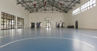 Basketbolcular spor salonunda antrenman yapıyor, pas veriyor ve enerjik bir şekilde koşuyor. Sporcular, takım çalışması, spor, antrenman, top sürme, antrenman