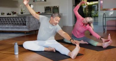 Yoga minderlerinin üzerinde uzanan, çok ırklı son sınıf çifti evdeki oturma odasında birlikte egzersiz yapıyor. Sağlık, fitness, egzersiz, egzersiz, sağlıklı, yaşam tarzı