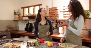 Mutfakta, evde sebze hazırlarken gülen iki çok kültürlü bayan arkadaş. Yemek, arkadaşlık, tatil, kutlama, yemek hazırlama