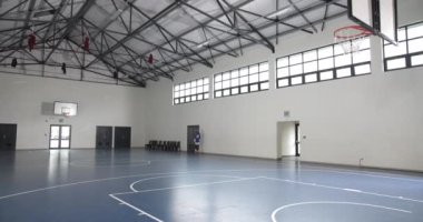 Basketbolcu, kapalı bir salonda tek başına antrenman yapıyor, yeteneklerine odaklanıyor. Sporcu, antrenman, spor, ithaf, konsantrasyon, motivasyon