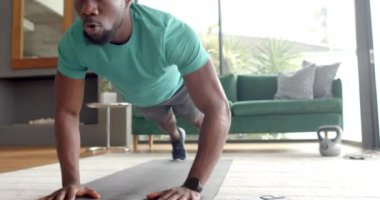 Güçlü ve formda bir Afrikalı Amerikalı egzersiz için oturma odasında şınav çekiyor. Spor, egzersiz, ev egzersizi, güç, eğitim, sağlık, değişmemiş, yaşam tarzı