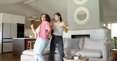 Dans ve kahkaha, iki farklı kadın arkadaş oturma odasında eğleniyor. Arkadaşlık, mutluluk, eğlence, eğlence, kaynaşma, kapalı alan