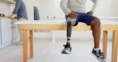 Muayene masasında oturan, protez bacaklı bir adam laboratuarda bekliyor. Sağlık, tıbbi, protez, hasta, laboratuvar, teknoloji
